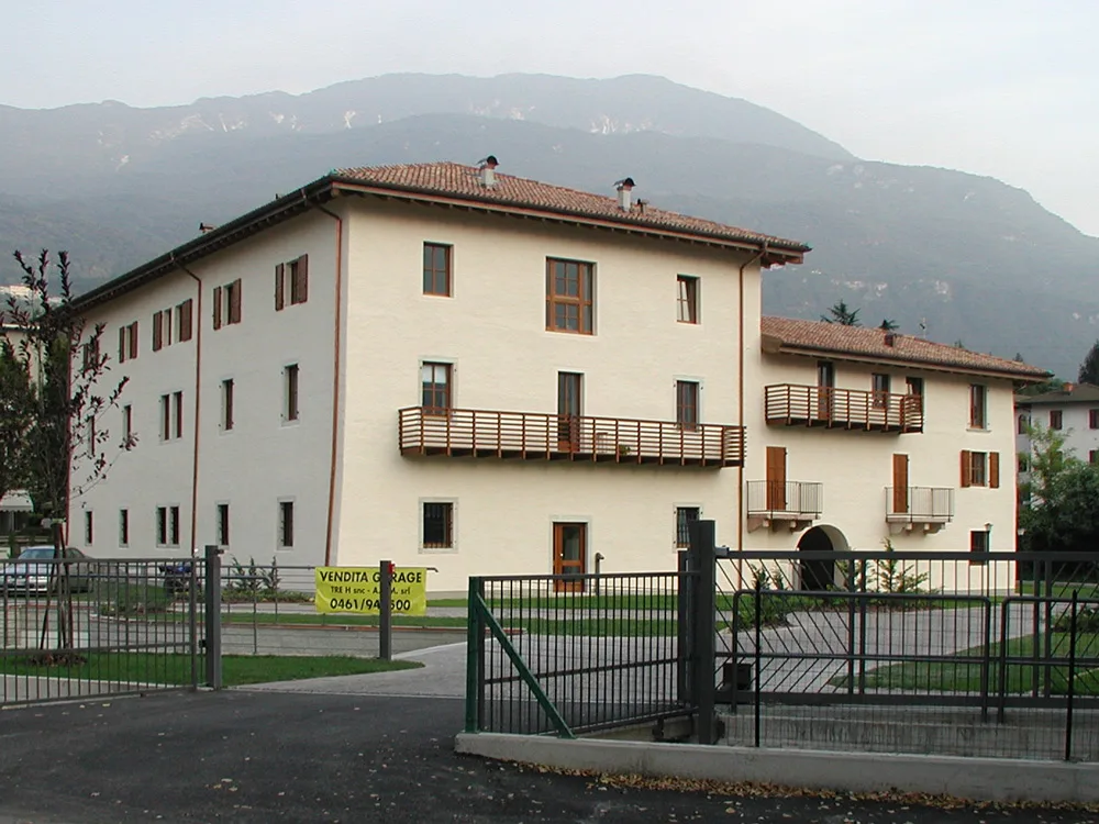 Maso Fogaroli a Trento, grande edificio chiaro ristrutturato dalla 3H, con le montagne dietro