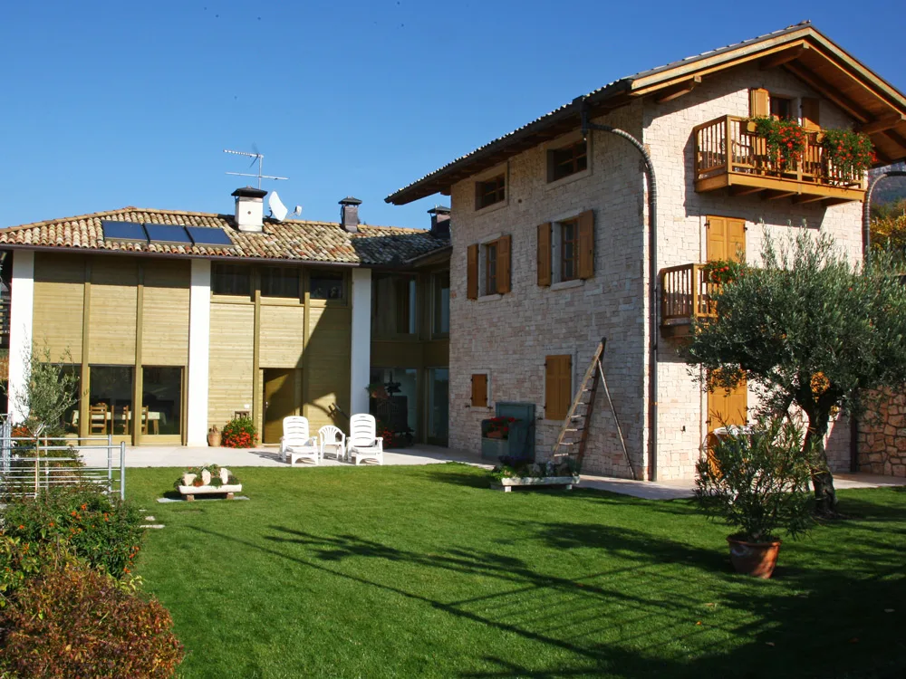 Villa privata a Oltrecastello costruita dalla 3H: casa in pietra con balconi in legno, prato e ulivo